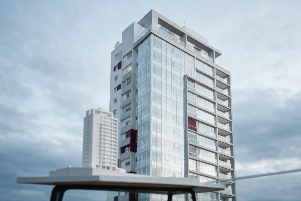 Edifício residencial moderno visto de baixo, com maquete em primeiro plano