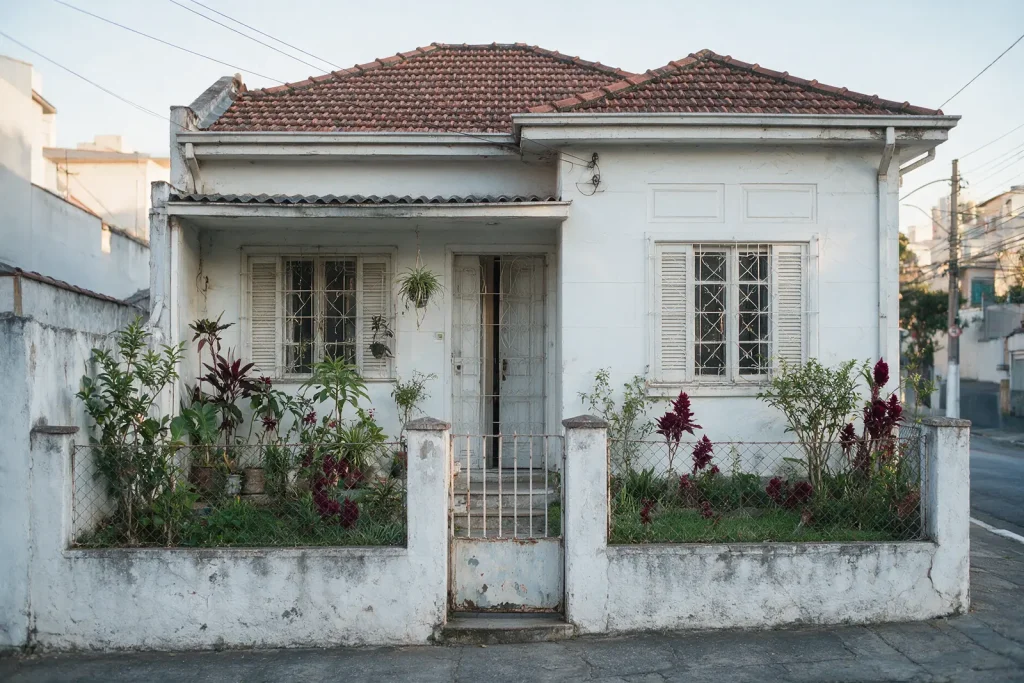 Casa antiga bem cuidada, com jardim e portão, em rua residencial de São Paulo